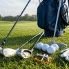 A complete beginner golf kit laid out on green grass, including entry level golf clubs, a stand bag, golf balls, tees, and a glove, ready for a first round in 2026