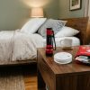 A bedside table with a flashlight, smoke detector, and small emergency kit set up for bedroom safety