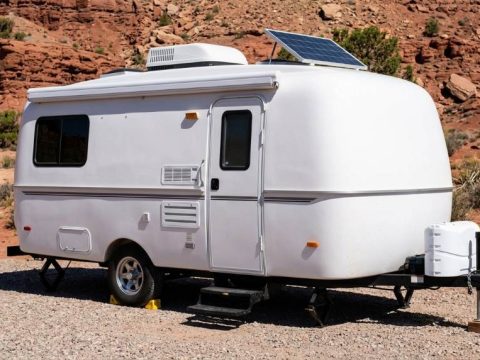 Camper parked under desert cliffs in Moab during summer heat