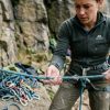 Climber carefully inspecting a dynamic rope outdoors in bright daylight.