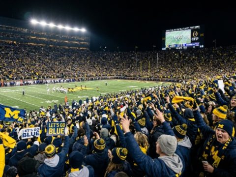 Packed college football stadium crowd cheering during a 2026–27 College Football Playoff first-round game played at a campus home site in December 2026