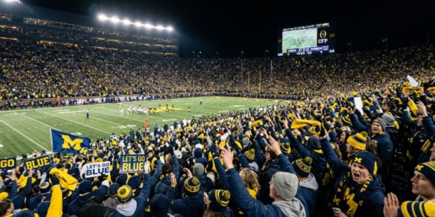 Packed college football stadium crowd cheering during a 2026–27 College Football Playoff first-round game played at a campus home site in December 2026