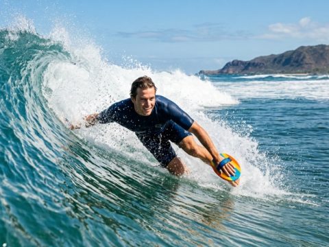 Surfer riding a blue ocean wave using a wooden bodysurfing handplane.