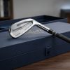 Polished custom iron golf club resting on a luxury gift box.