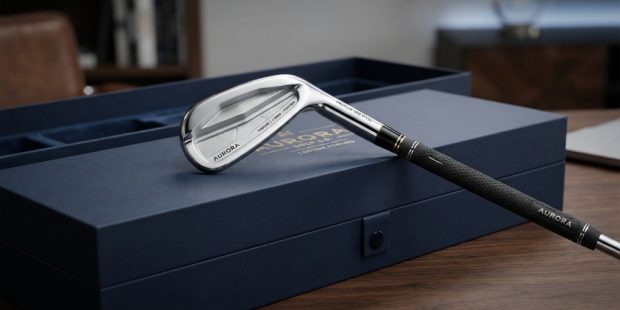 Polished custom iron golf club resting on a luxury gift box.