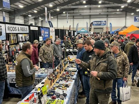 Anglers browsing ice fishing rods and reels at a crowded winter show