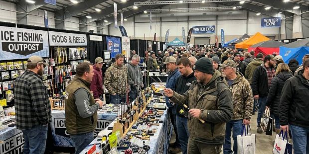 Anglers browsing ice fishing rods and reels at a crowded winter show